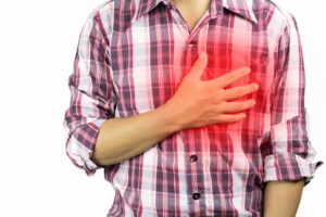 Man in plaid shirtt holding chest due to heart disease.