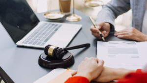 A solicitor sat with a laptop and clipboard discussing a potential claim for hip replacement medical negligence with their client