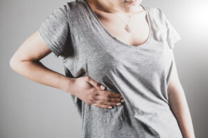 Woman in grey shirt holding chest.