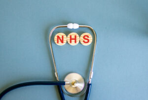 A stethoscope with 'NHS' written on wooden blocks in the centre. This represents the responsibilities of the NHS as a service provider