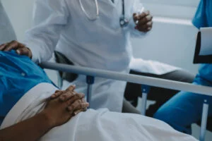 Visual of a medical professional consulting with a patient by their bed.