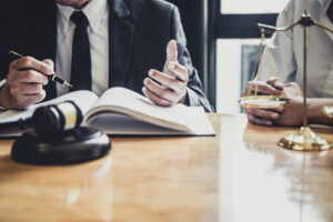 A pair of No Win No Fee solicitors sit at a desk while discussing a case against an NHS foundation trust. The claimant they are representing has already followed the NHS complaints policy but they require further practical advice
