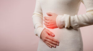 A woman holding her stomach who was told she was suffering from heavy periods and severe period pain but it was a missed diagnosis and was actually endometriosis.
