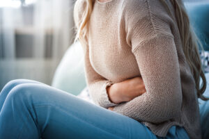 A woman is holding her stomach in significant pain and is considering filing a endometriosis negligence claim.